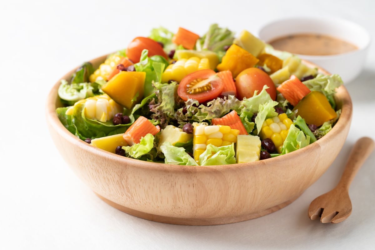 Insalata di verdure fresche in ciotola di legno su fondo chiaro