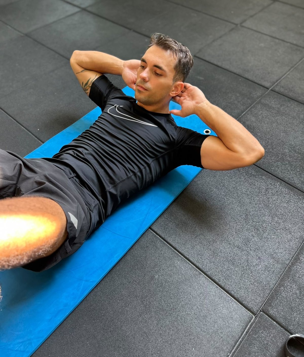 Uomo che esegue addominali su un tappetino blu in palestra